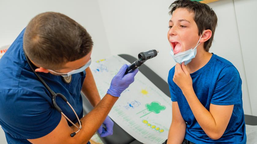 A doctor looks at a boy's throat during an exam