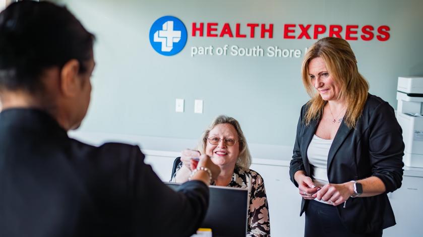 A female patient checks in at the front desk at Health Express urgent care