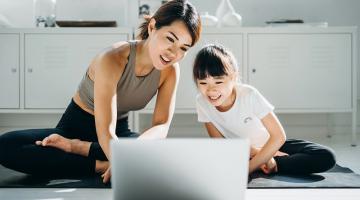 Asian woman and her daughter getting ready to do a virtual exercise class in front of a laptop