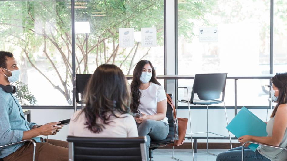 A group of people meets wearing masks and while observing social distancing