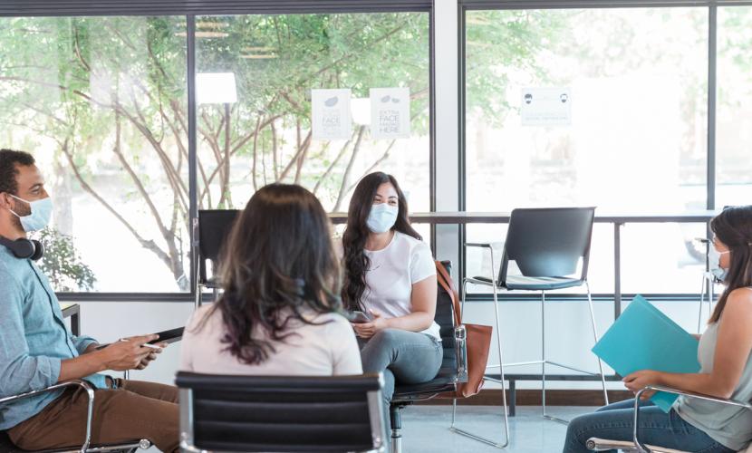 A group of people meets wearing masks and while observing social distancing