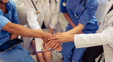 Doctors and nurses huddle and join hands