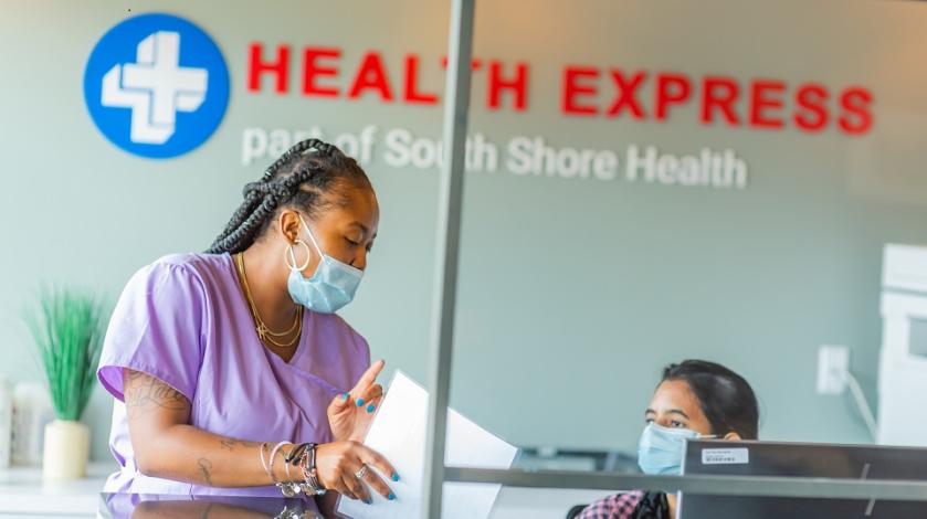 Two female Health Express staff members speak at the front desk