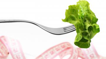 Lettuce on a fork with a tape measure in the background