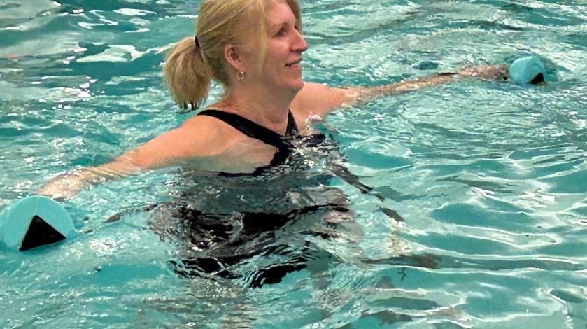 A woman exercising with weights in a pool class
