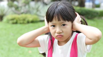 A little girl covers her ears due to sensory sensitivities