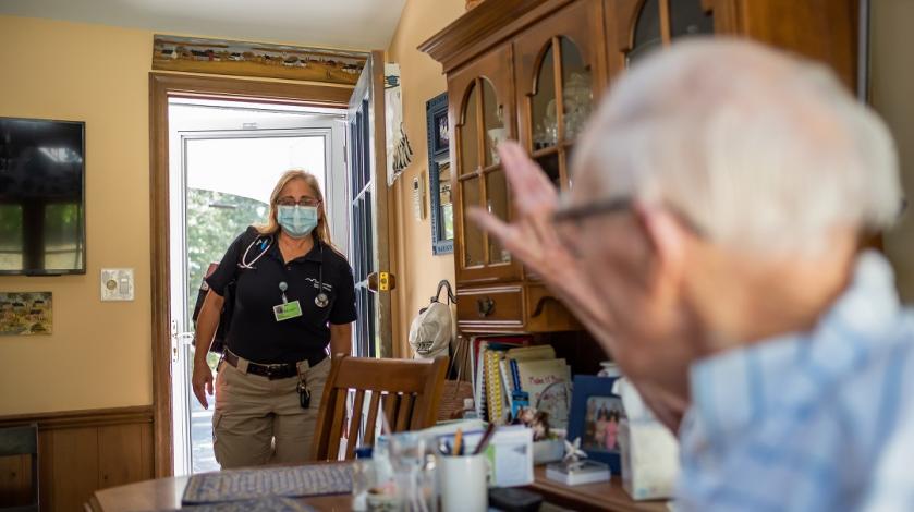 A female paramedic with Mobile Integrated Health cares for elderly man in his home