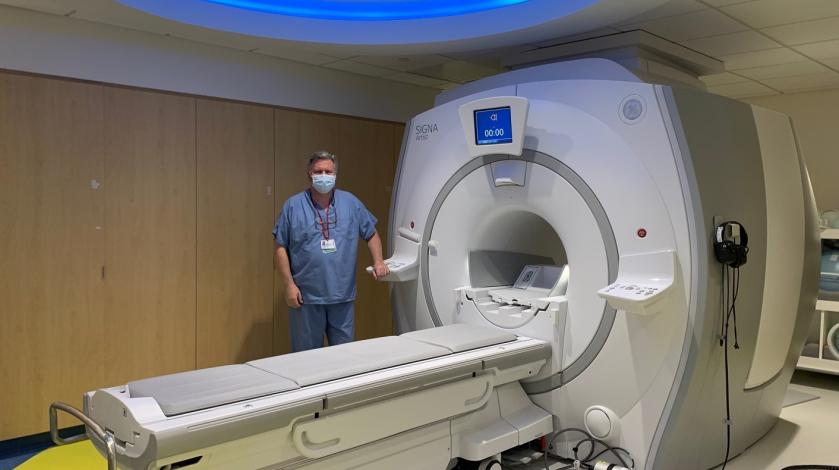 An MRI technologist stands next to a new MRI machine