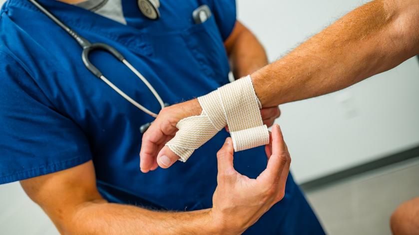 A provider wraps an ace bandage around an older male patient's wrist