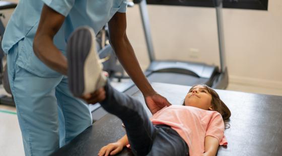 Pediatric patient doing a leg stretch as part of physical therapy