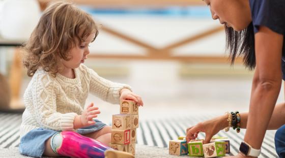 A young girl playing with blocks with an occupational therapist