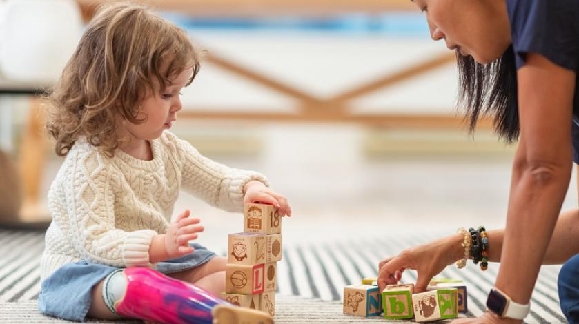 A young girl playing with blocks with an occupational therapist