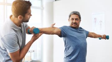 A patient holding a weight while working with a physical therapist