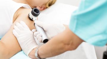 A doctor examines a female patient's arm during a skin cancer screening