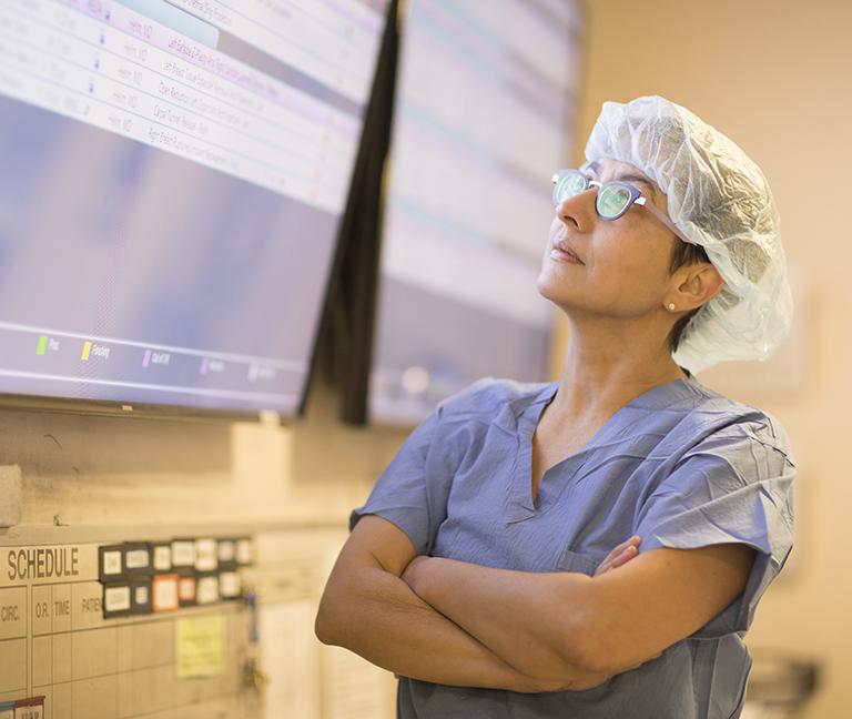 Doctor wearing scrubs looks up at screen