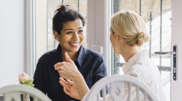 two young women talking in a cafe over coffee