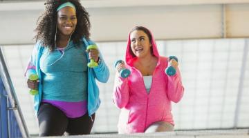 Two women walking together with weights