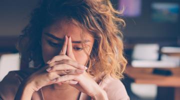 A stressed woman sits quietly and thinks